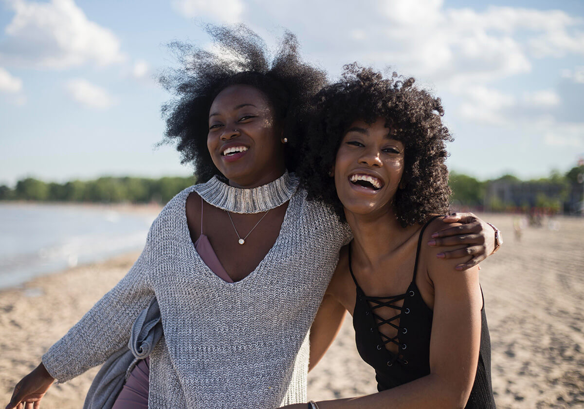 Two midlife women laughing on a beach