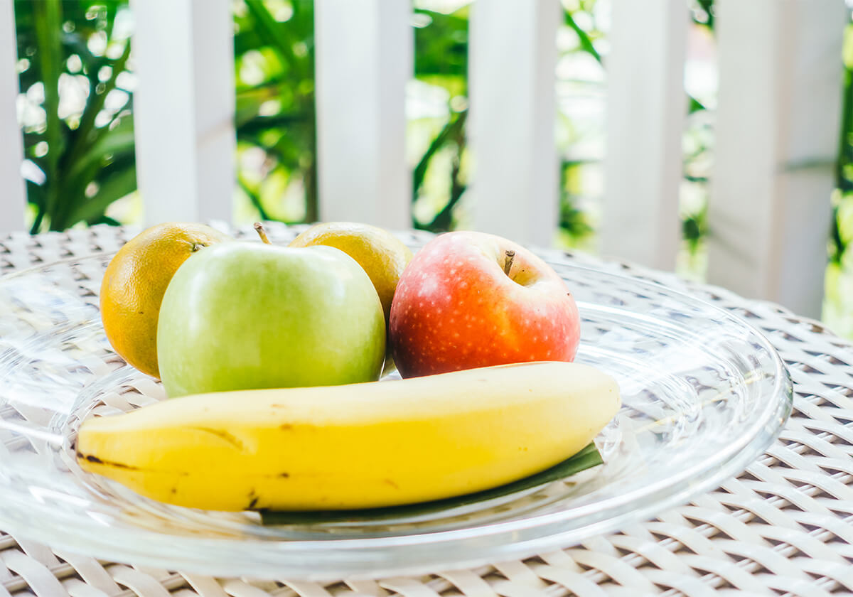 Fruit on plate on white table with garden visible in background