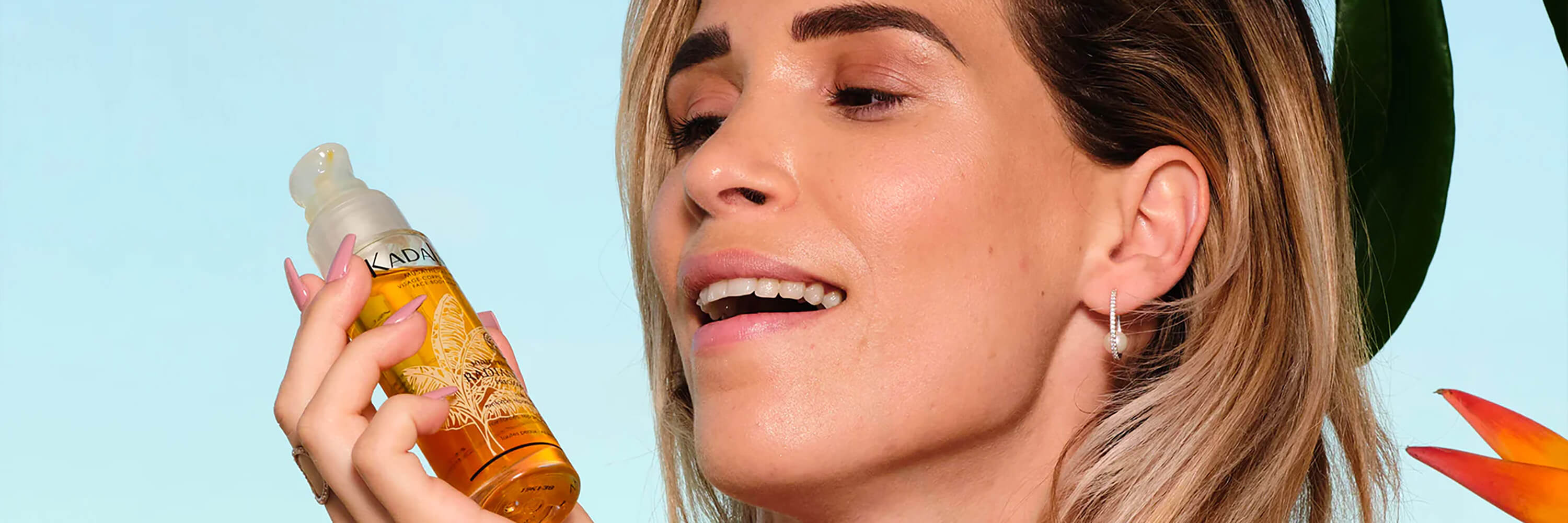 Image of woman holding Kadalys Radiance Oil against a light blue background | Best selling Kadalys natural skincare products made with Banana Bio-Actives
