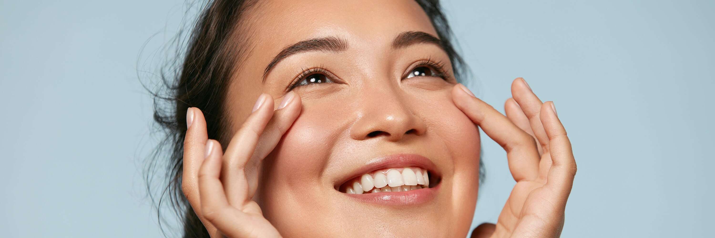 woman smiling while touching her under eye area | Kadalys natural lip and eye products