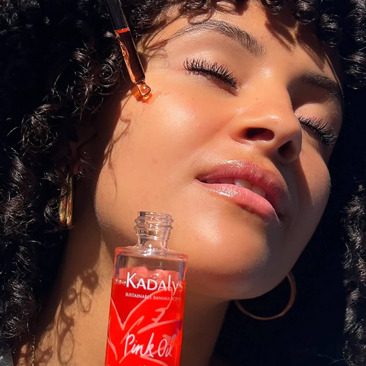 model holding pink banana serum vegan, organic, and upcycled skincare line