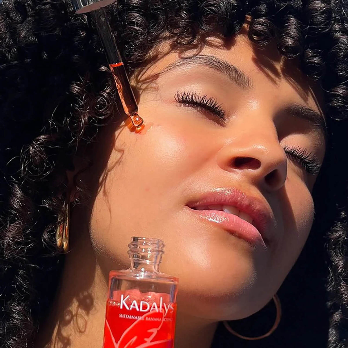 IMAGE: Woman applying Kadalys Pink Banana Glow Booster Serum to her face