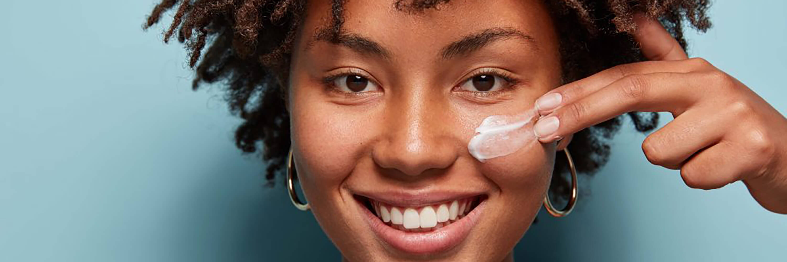 Black woman applying cream to her face | Kadalys natural moisturizers and creams for dry and dehydrated skin concerns