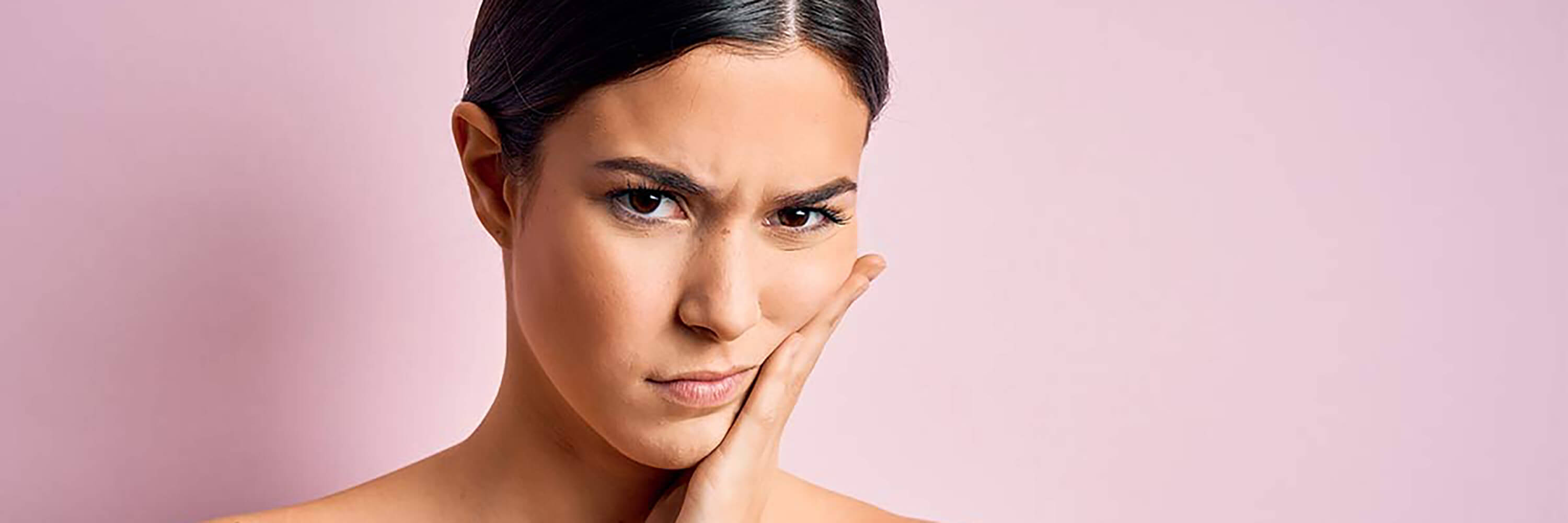 images of woman touching sensitive skin in front of pink background | Sensitivity and redness products