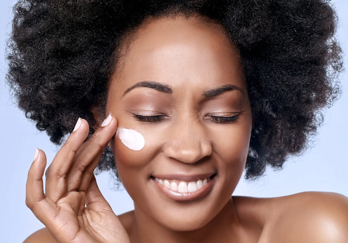 Beautiful Black woman applying cream to her face