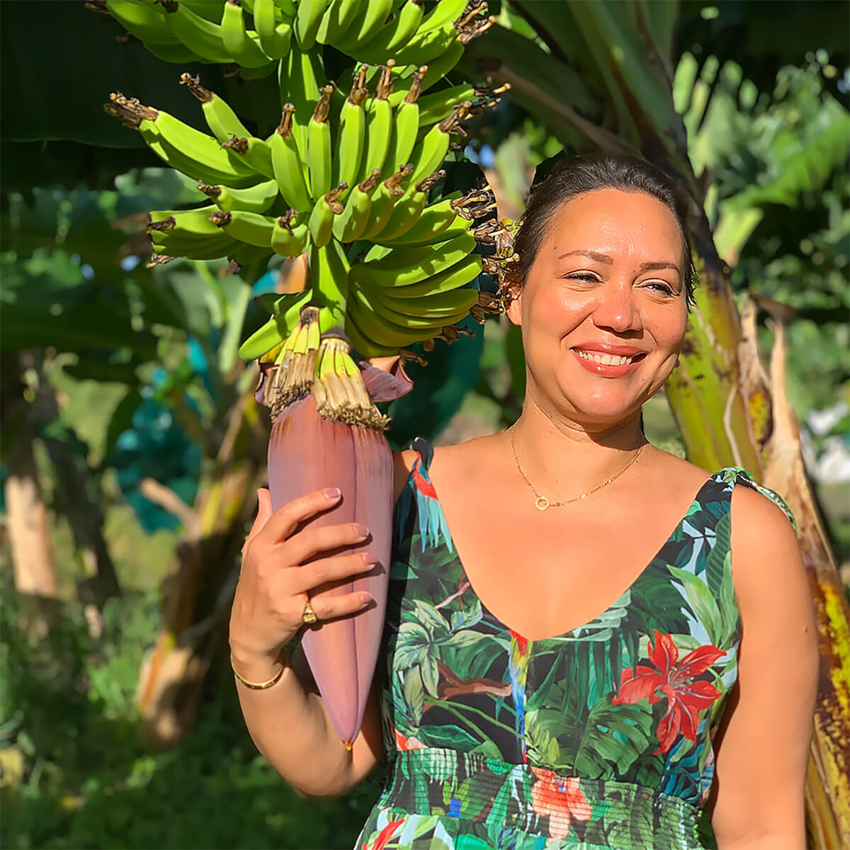 Kadalys Founder Shirley Billot standing next to pink banana plant. Blurred images of additional banana trees are in the background.