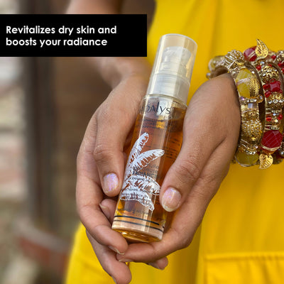 Image of a Black woman’s hands holding a bottle of the dry face oil against the background of her yellow dress. Caption calls out this is a revitalizing dry face oil for radiant skin.