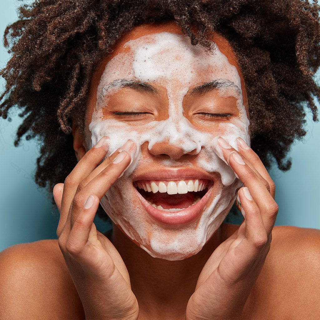 Woman washing face with cleanser
